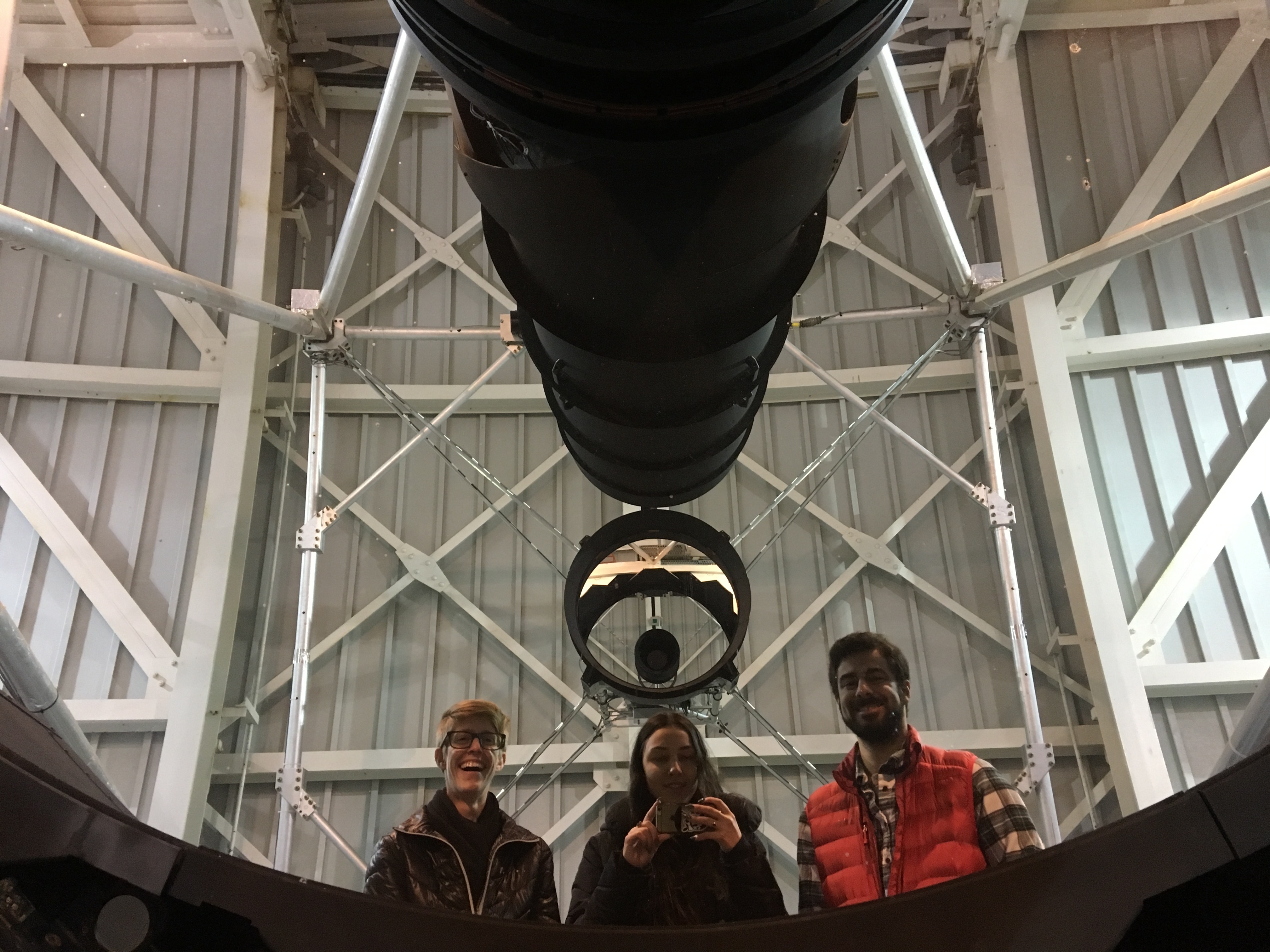Image of three graduate students in front of the the 3.5 meter APO telescope. 